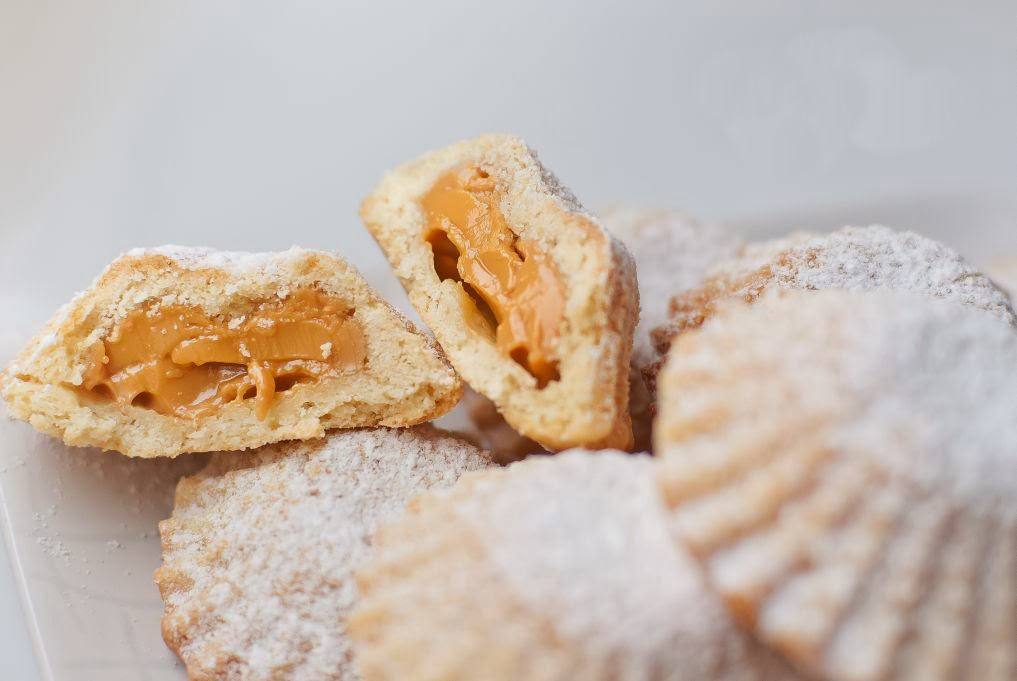 Kruche babeczki obsypane cukrem pudrem, przekrojone z masą krówkową