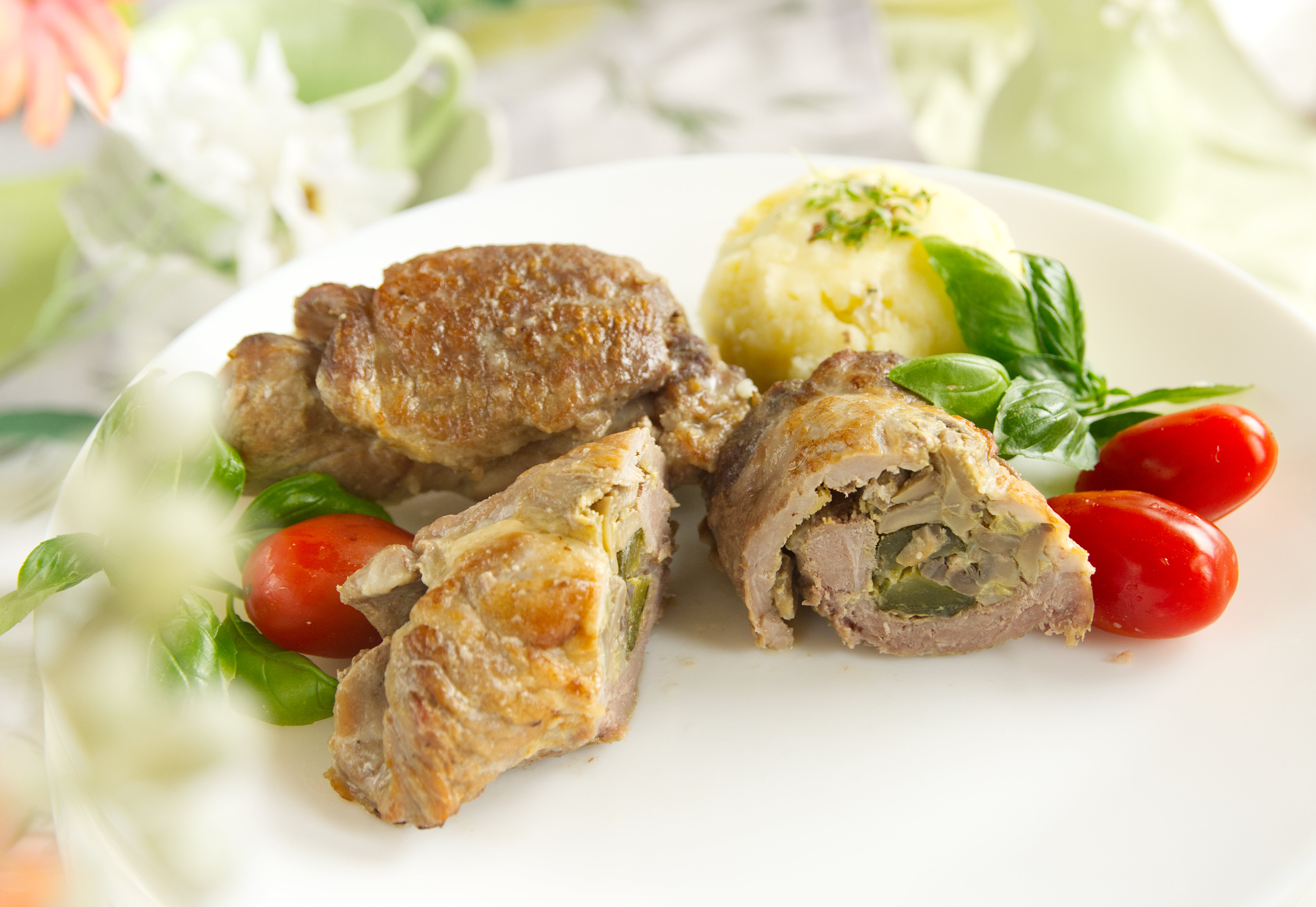 mięsne roladki podane na talerzu z pomidorkami