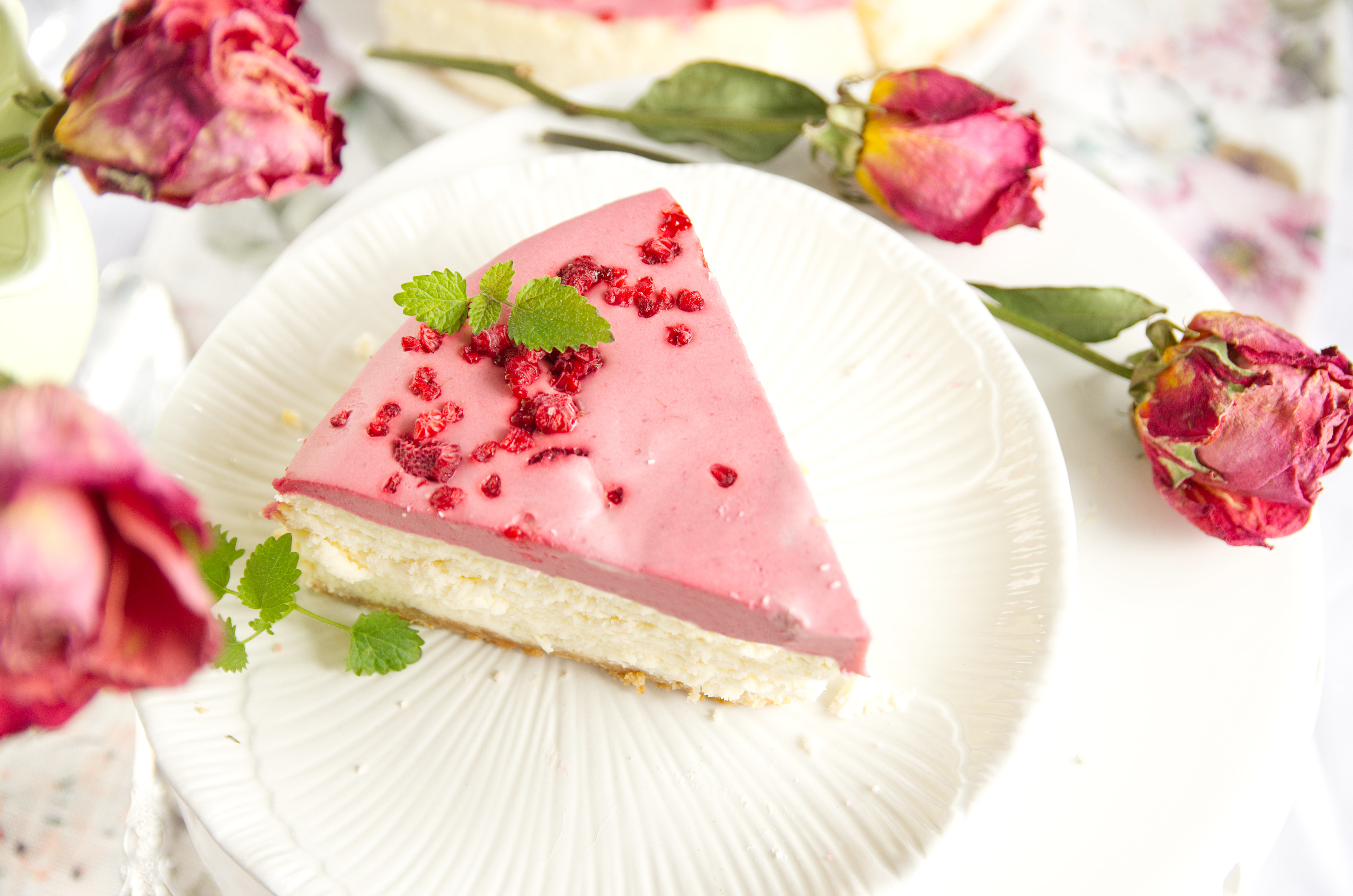 kawałek sernika z malinowym musem , obok czerwone róże
